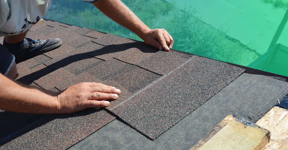 hands installing shingles on roof 